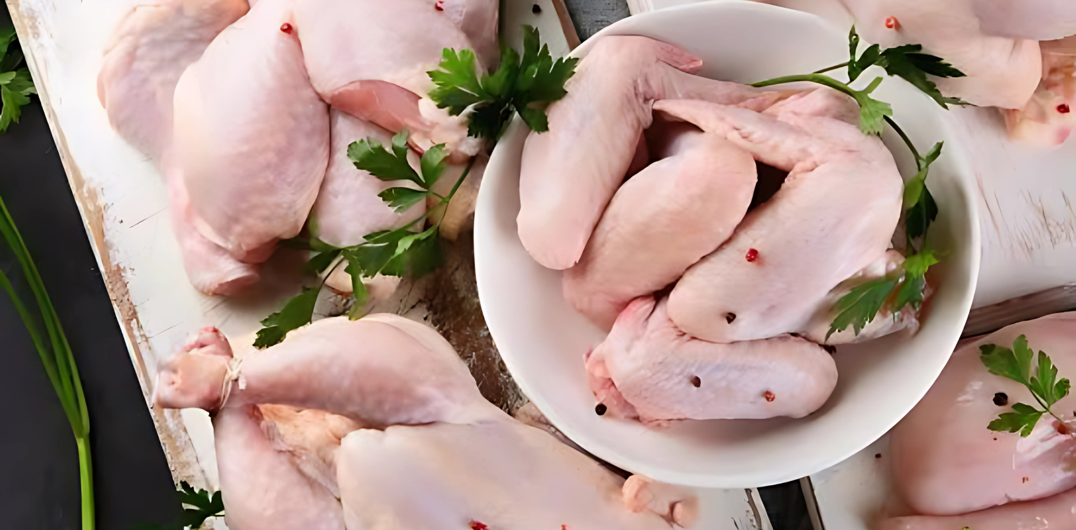 Fresh raw chicken breast fillets neatly arranged on a wooden board with herbs – perfect for meal prep or grilling.